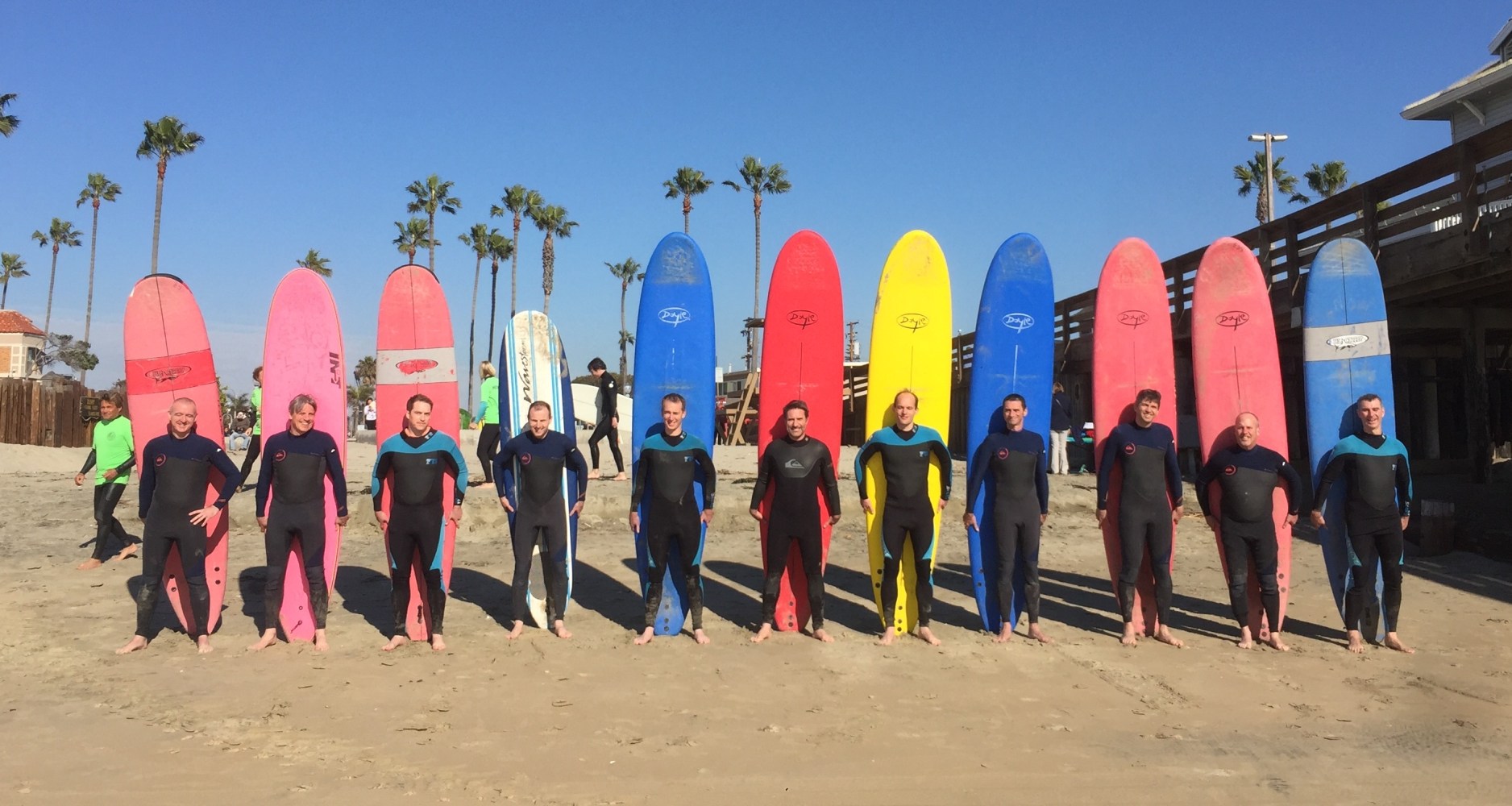 a group of people standing on a beach posing for the camera in front of surf boards